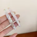Detalle en primer plano de horquilla de acrílico jaspeado con letras doradas, elegante. - Horquilla / Blanco