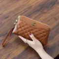 Brown genuine leather quilted clutch bag with metal bee emblem and wrist strap for women. - Caramel color