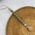 Silicone wooden pacifier clip detail view, featuring safe teeth beads for infant daily use. - Bean Green
