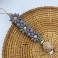 Grey silicone flower pacifier clip with natural wooden beads and secure metal clip. - Gray