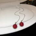 Close-up of elegant long chain drop earrings featuring smooth red sphere pendants inside a white box. - Ball Tassel Ear Threader Style / Red