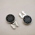 Detailopname van ronde zwart-zilveren decoratieve metalen knopen met klassiek bloemmotief. - Zilver