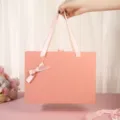 Pink gift box with ribbon handle and bow, perfect for packaging candy, lipstick, and small gifts. - Large Size 27*20*8.8cm / Pink Gift Box with Gold-Edged Bow