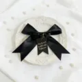 Black satin bow ribbon with gold stamped tag detail for gift box decoration and craft packaging. - Approx 4x53cm / Black