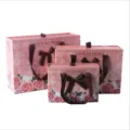 Detailed view of pink drawer gift boxes with floral prints, brown bows and carry handles. - 27x20x8.8cm