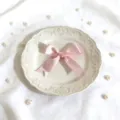 Primer plano de lazo de cinta de satén rosa en plato vintage decorativo con perlas para regalos. - Rosa