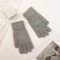Nahaufnahme von kuscheligen Strickwinterhandschuhen in Grau mit Webbuchstaben,weich. - Grau