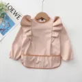 Detailaufnahme des wasserdichten Babylätzchens mit langen Ärmeln und niedlichen Engelsflügeln. - Größe S (6-12 Monate) / Langärmelig mit rosa Flügeln