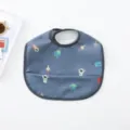 Detailed view of waterproof baby dining bib with cute space astronaut pattern and handy pocket. - Dark Gray Astronaut