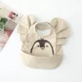 Detail view of waterproof baby bib with cute penguin graphic, ruffles, and crumb catcher pocket. - Placed Print Penguin Wings