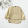 Vista detallada del babero impermeable de manga larga dorado para bebés durante las comidas. - Dorado