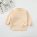 Vista detallada de babero con mangas impermeable para bebé con bolsillo color albaricoque. - Rosa carne