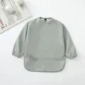 Detalle del babero impermeable para bebé de manga larga con práctico bolsillo atrapa migas. - Verde Salvia