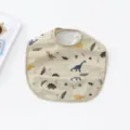 Danish style PU waterproof baby bib with cute dinosaur print and crumb catcher pocket main view. - Beige Dinosaur