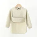 Detaillierte Ansicht des wasserdichten Baby Langarm PU Lätzchens mit Tasche und Knöpfen. - Größe S (6–12 Monate) / Zweireihige PU-Langarmjacke mit Tasche - Beige