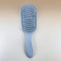 Detailed view of the curved hair brush with flexible bristles for comfortable scalp massage and styling. - Grey Blue