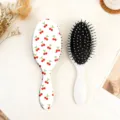 Vue détaillée de la jolie brosse à cheveux ovale à motif cerise avec des picots doux pour les soins. - Cerise