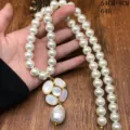 Primer plano del colgante camelia de nácar y los detalles del collar de perlas largas. - Collares de cuentas FM954