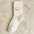 Gros plan détaillé de chaussettes en peluche blanche douillettes avec motif de cœur brodé. - Taille unique / Blanc Laiteux