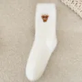 Gros plan sur des chaussettes d'hiver blanches et duveteuses avec broderie mignonne. - Taille unique / Blanc