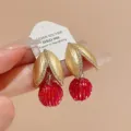 Detailaufnahme von goldenen Blättern und roten Perlen Ohrringen mit feiner Verarbeitung. - Goldrot (Blume)