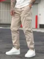 Close-up detail of men's khaki cargo pants featuring multi pockets and elastic cuffs. - S / Khaki