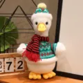Simpatico peluche di anatra con maglione invernale e cappello, decorazione natalizia. - Anatra seduta con sciarpa a righe rosse