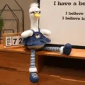 Simpatico giocattolo in peluche di anatra a gambe lunghe con occhiali e abito in denim decoro. - Anatra a zampe lunghe con occhiali - Vestito salopette di jeans