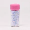 Primer plano de lentejuelas con purpurina para uñas iridiscentes en frasco de vidrio con tapa rosa. - Blanco