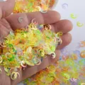 Close up of holographic star and moon nail sequins glittering on hand for DIY craft design. - Multicolor