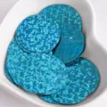 Close-up of 25mm blue holographic round sequin paillettes with side hole for DIY crafts and clothing. - Laser Lake Blue