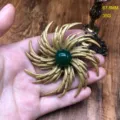 Close-up detail of vintage gold-plated sunburst brooch featuring a green gemstone centerpiece. - Green Agate Brooch