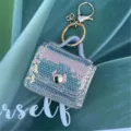Dettaglio del mini portachiavi a borsa con paillettes iridescenti su foglia - portachiavi per borse / Ricamo Piatto Grigio