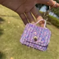 Close-up of a purple sequined mini bag keychain charm held outdoors in natural light. - Bag Charm / Embroidered Purple