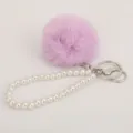 Close-up detail of fluffy pom-pom and pearl bracelet keychain, cute plush bag pendant. - Purple Pompom Pearl Keychain