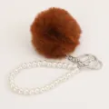 Detail view of brown plush pom pom and white pearl bracelet keychain ornament. - Brown Pompom Pearl Keychain