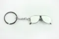 Gedetailleerde close-up van creatieve zilveren metalen zonnebril hanger aan sleutelhanger. - Wit