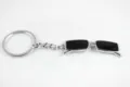 Close-up van creatieve mini zonnebril sleutelhanger hanger met zwarte lenzen en zilveren ring. - Zwart