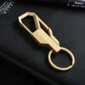 Gedetailleerd overzicht van gouden metalen autosleutelhanger, stijlvolle geometrische ring. - Goud