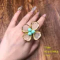 Primer plano de un elegante anillo de flor ajustable con pétalos translúcidos y perlas. - Anillo HE909-2