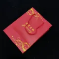 Vue détaillée d'un sac cadeau à bijoux rouge en papier avec motif floral doré élégant. - Pochette à bijoux rouge