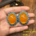Primer plano detalle de pendientes vintage ovales naranjas con borde de cristal azul. - Pendientes de Botón Azules