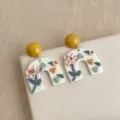 Nahaufnahme von handgefertigten Polymer-Ton Blumen Bogen Ohrringen mit gelbem Kugelstecker. - Rosa Blumenohrringe (6161)