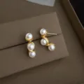 nahaufnahme detailansicht von eleganten perlen ohrringen mit geschwungenem gold design - Geometrische Perle Ohrstecker (4049)