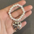 Handgemachtes weißes Kunstperlenarmband als Accessoire mit silbernem hohlem Herzanhänger - Hohler Herz-Stil (16号款) / 1 Stück