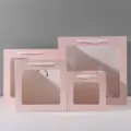 Vierkante roze papieren cadeauzakjes met doorzichtige vensters en witte lint handgrepen, voorzijde. - 15x15x15cm / Roze