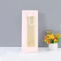 Sac cadeau en papier rose avec fenêtre transparente, sac à vin avec poignées blanches. - Rose
