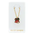 Gedetailleerde close-up van een feestelijke kerstbel sleutelhanger met gouden kralenketting. - Kerstbel