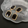 Close-up detail of vintage style gold-rimmed black crystal drop earrings, elegant craftsmanship. - Earrings / Gold