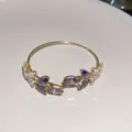 Elegantes goldenes Armband mit offenen Enden, verziert mit lila und klaren Kristallblättern. - Armreif mit Blattmuster Nr. 10 – Lila